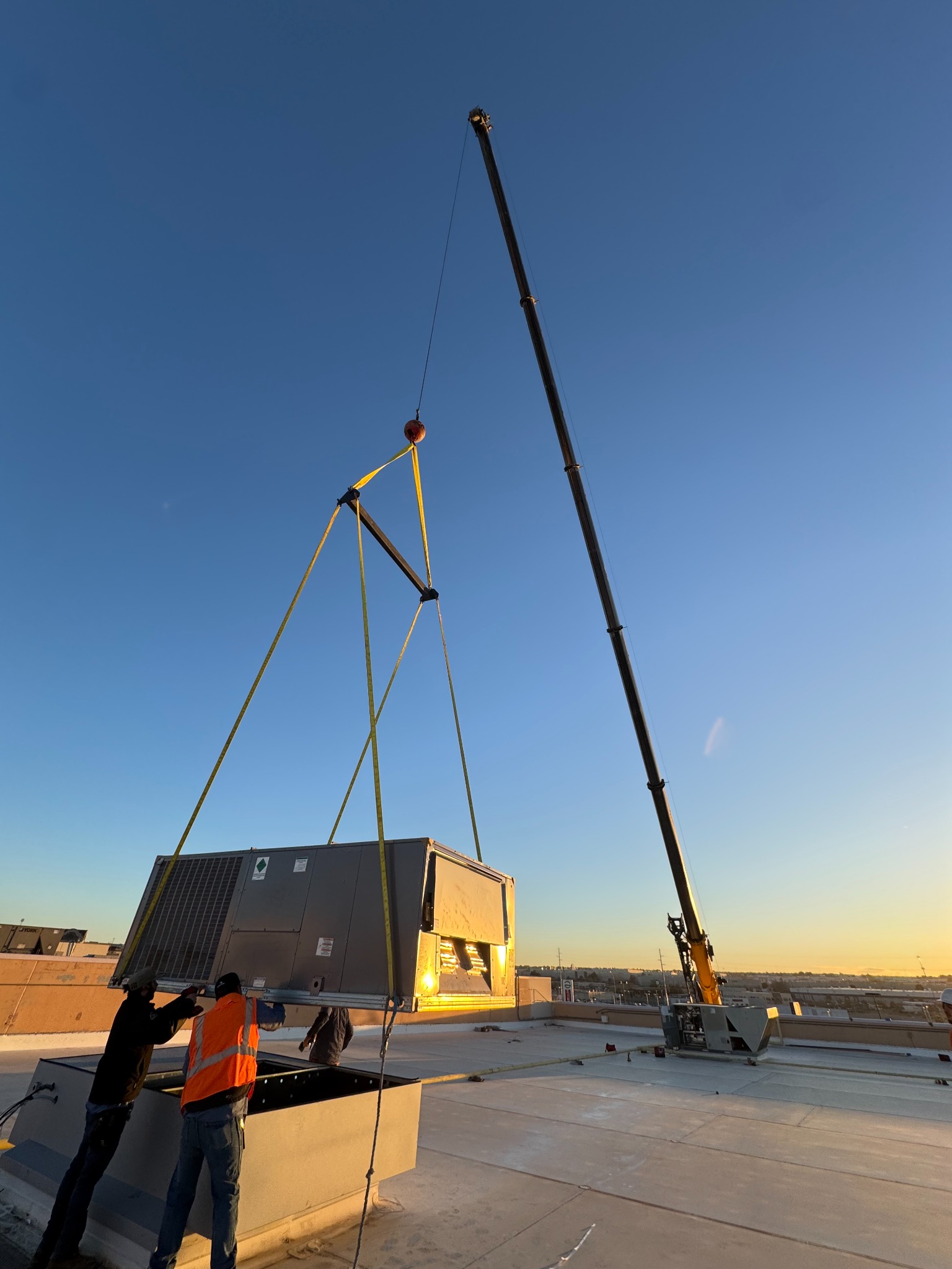 Large crane lifting a rooftop HVAC unit during the Clint ISD modernization project